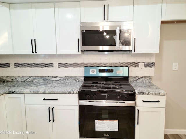 kitchen featuring light stone counters, stainless steel appliances, and white cabinets