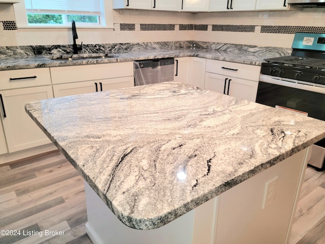 kitchen with sink, appliances with stainless steel finishes, light hardwood / wood-style floors, and white cabinetry