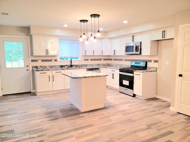 kitchen with a center island, white cabinets, appliances with stainless steel finishes, decorative light fixtures, and light stone countertops