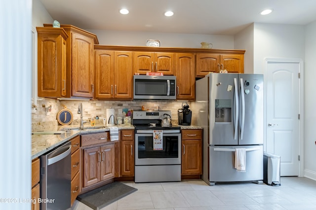 kitchen with sink, stainless steel appliances, tasteful backsplash, light stone counters, and light tile patterned floors