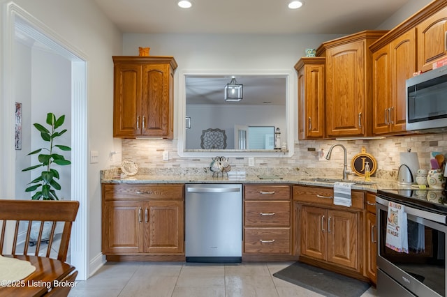 kitchen featuring backsplash, sink, appliances with stainless steel finishes, light tile patterned flooring, and light stone counters