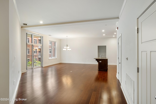 unfurnished room with an inviting chandelier, dark hardwood / wood-style flooring, and ornamental molding