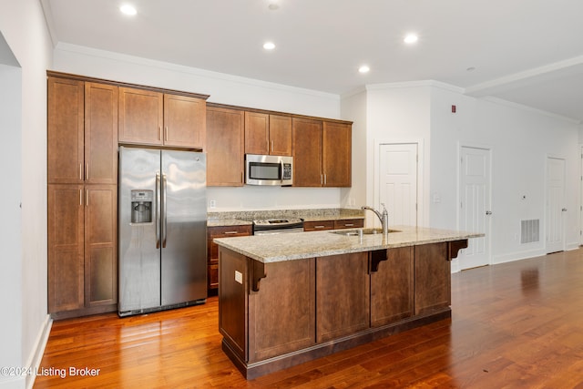 kitchen featuring a center island with sink, hardwood / wood-style flooring, a kitchen bar, appliances with stainless steel finishes, and sink