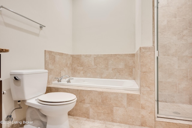 bathroom with a relaxing tiled bath, tile flooring, and toilet