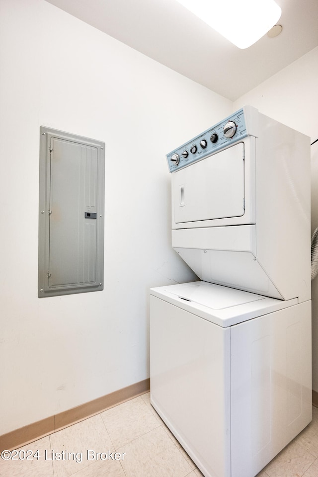 clothes washing area featuring stacked washer and clothes dryer and light tile flooring