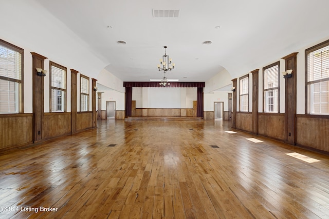 spare room featuring wood walls, hardwood / wood-style floors, and a chandelier