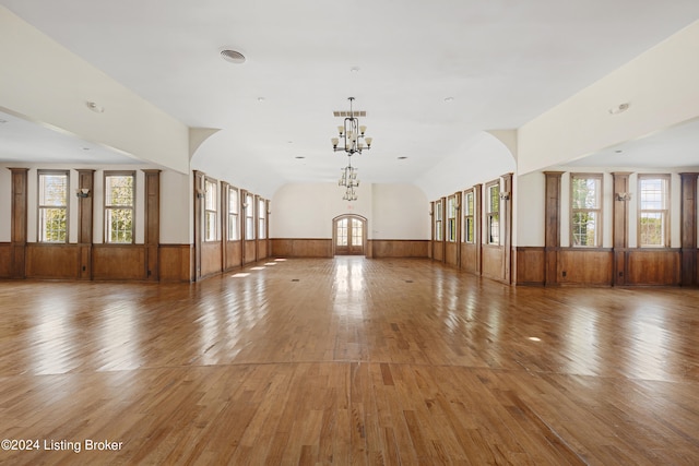 spare room with wood-type flooring, plenty of natural light, and a chandelier