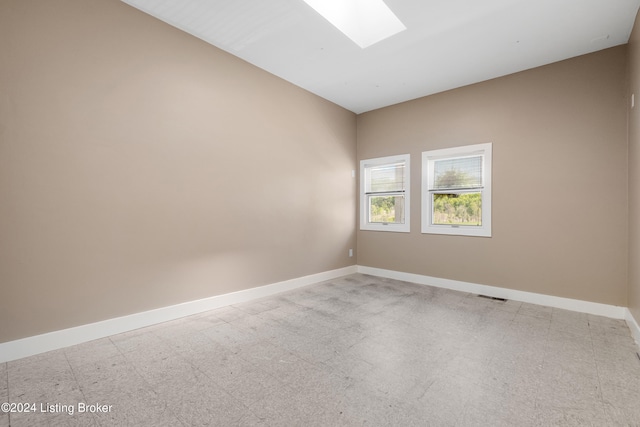 tiled empty room featuring a skylight