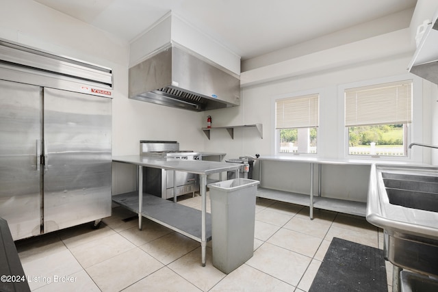 kitchen featuring appliances with stainless steel finishes, wall chimney exhaust hood, and light tile flooring