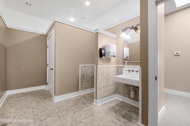 bathroom with tile flooring, a skylight, and sink