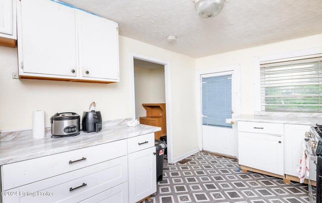 kitchen featuring gas range, a textured ceiling, and white cabinetry