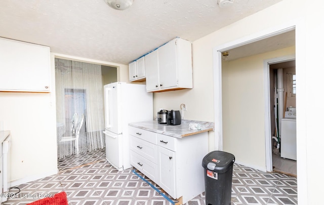 kitchen featuring white cabinets, white refrigerator, a textured ceiling, and washer / dryer