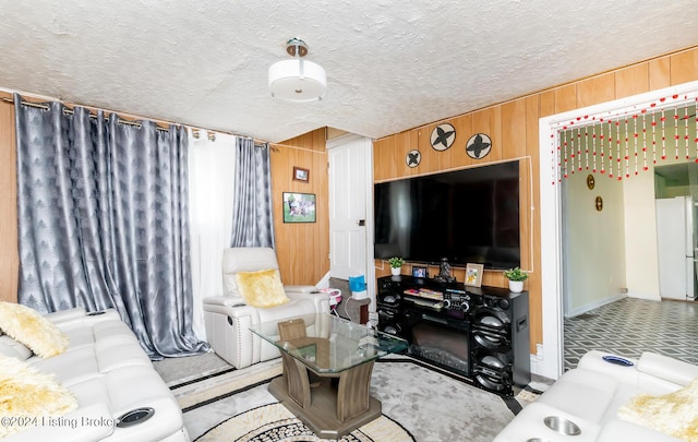 living room featuring a textured ceiling and wooden walls