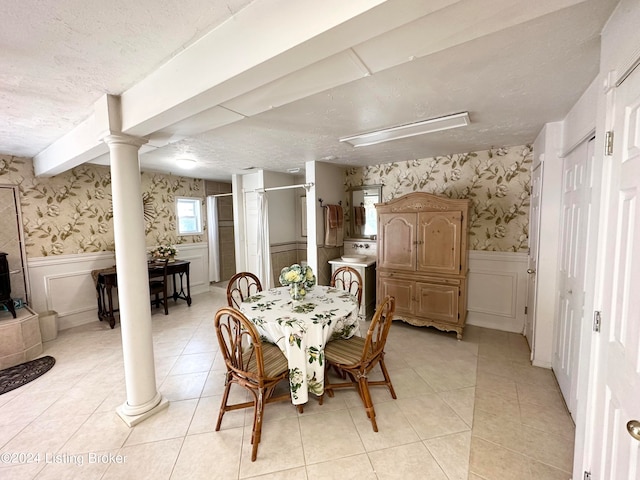 tiled dining space featuring beam ceiling, a textured ceiling, washer / dryer, and decorative columns