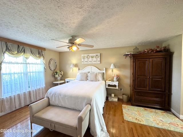 bedroom with a textured ceiling, ceiling fan, and hardwood / wood-style floors