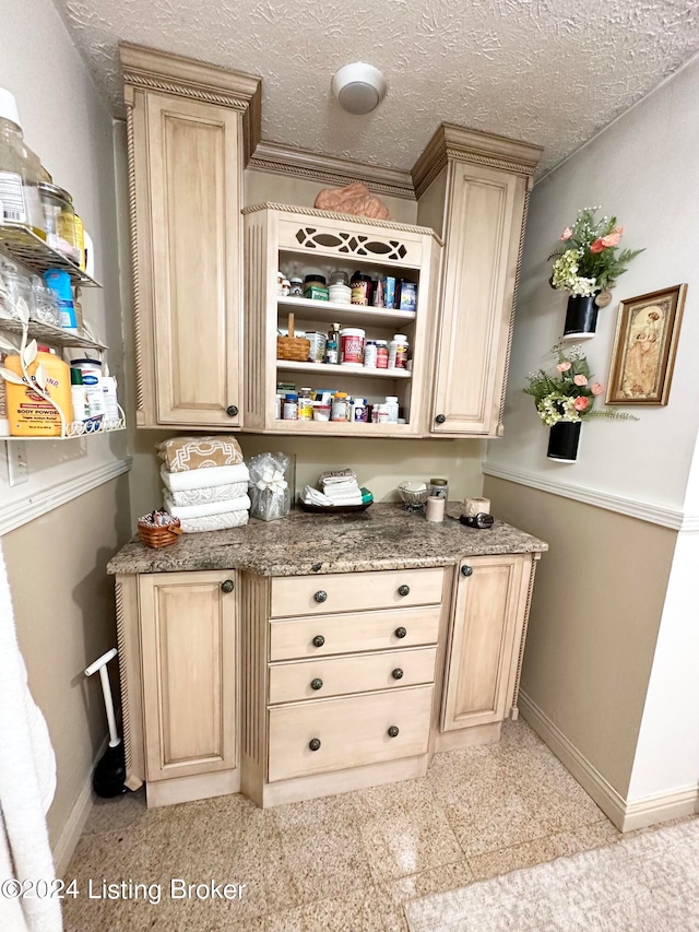 bar featuring light brown cabinets, a textured ceiling, and light tile flooring