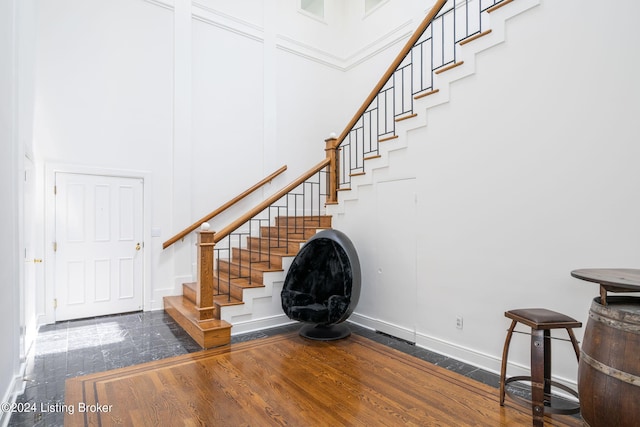 stairs with a towering ceiling and dark hardwood / wood-style flooring