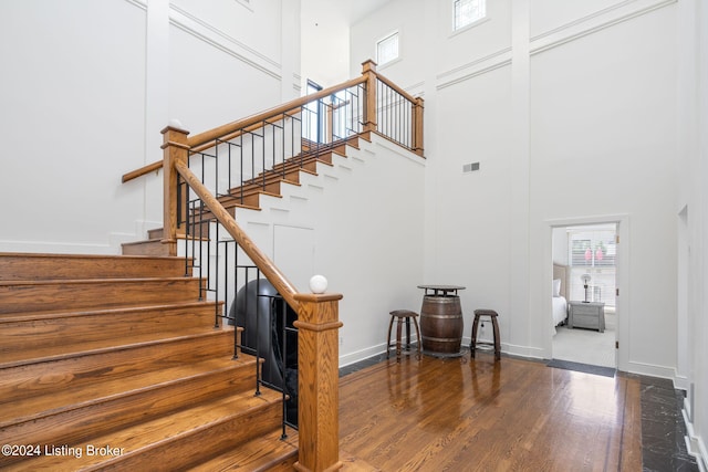 stairway with a high ceiling and hardwood / wood-style floors