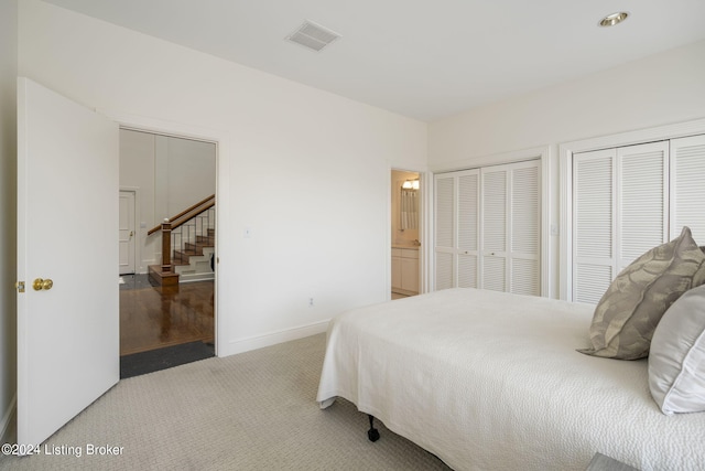 bedroom featuring carpet flooring, two closets, and ensuite bath