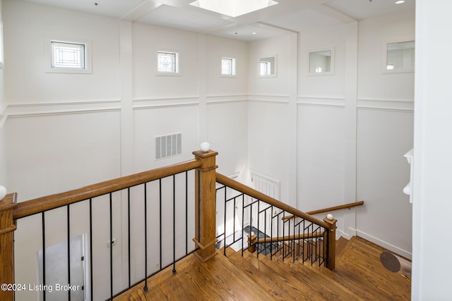 stairs featuring wood-type flooring, plenty of natural light, and a skylight