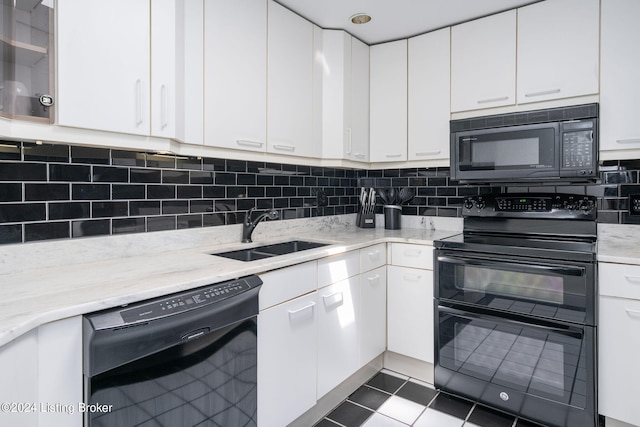 kitchen featuring white cabinetry, light stone countertops, black appliances, backsplash, and dark tile flooring