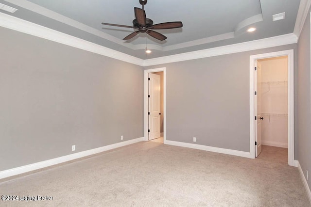 empty room featuring carpet flooring, ceiling fan, a tray ceiling, and crown molding