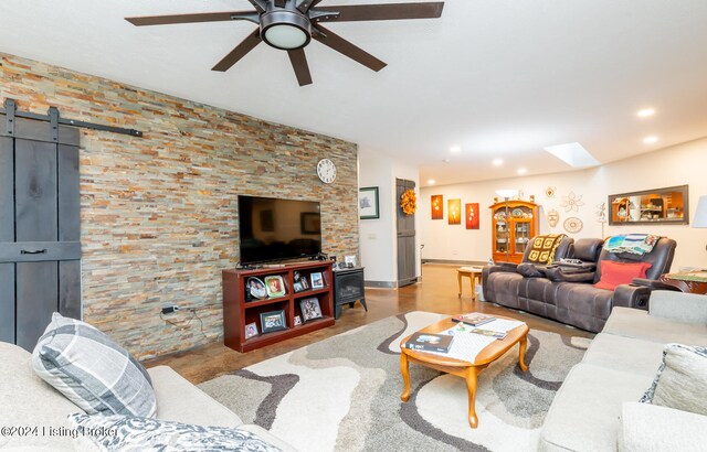 living room with a barn door and ceiling fan