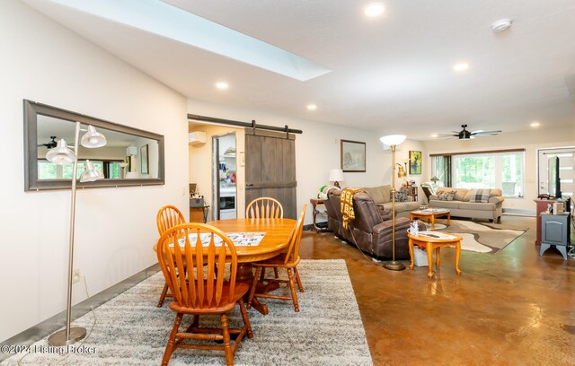 dining space with a barn door, a wall mounted AC, ceiling fan, and concrete flooring