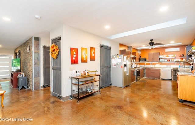 kitchen with appliances with stainless steel finishes, sink, a wall unit AC, and ceiling fan