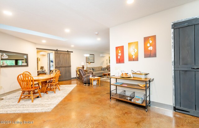 dining area with a barn door, concrete flooring, and a textured ceiling