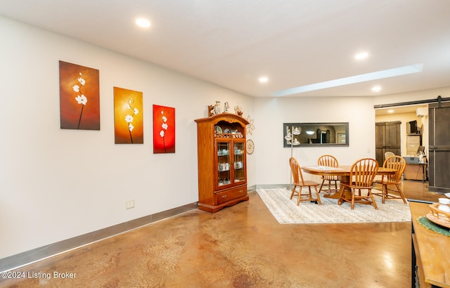 dining room with a barn door and concrete flooring