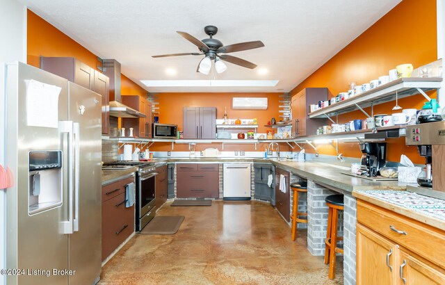 kitchen with wall chimney range hood, light brown cabinetry, stainless steel appliances, ceiling fan, and a wall mounted AC