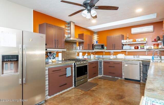 kitchen with a wall mounted air conditioner, stainless steel appliances, ceiling fan, wall chimney exhaust hood, and sink