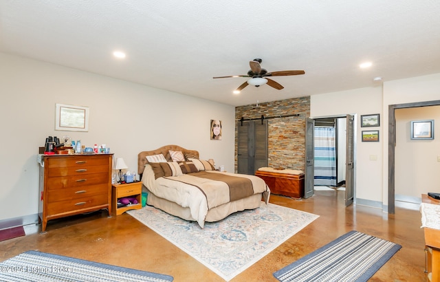 bedroom with a barn door, ceiling fan, and a textured ceiling