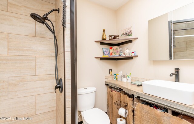 bathroom featuring a tile shower, vanity, and toilet