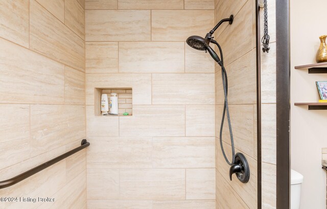 bathroom with a tile shower and toilet