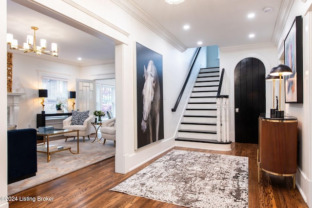 entrance foyer featuring dark hardwood / wood-style floors, an inviting chandelier, and ornamental molding