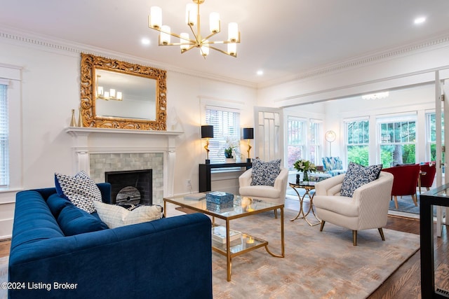 living room with ornamental molding, a fireplace, wood-type flooring, and a notable chandelier