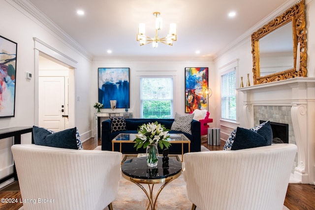 living room featuring dark wood-type flooring, a tiled fireplace, a notable chandelier, and ornamental molding