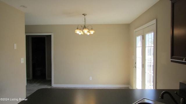 unfurnished dining area featuring sink, carpet floors, and an inviting chandelier