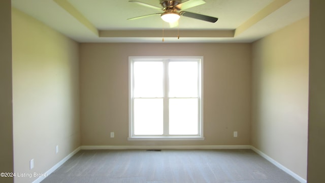 spare room featuring ceiling fan, a raised ceiling, and carpet floors