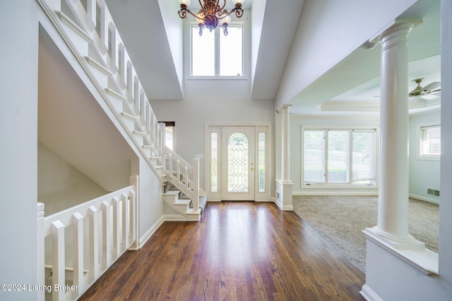 foyer with a high ceiling, ornate columns, a chandelier, and dark hardwood / wood-style floors