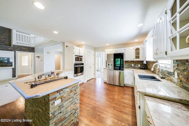 kitchen with sink, light wood-type flooring, decorative backsplash, white cabinetry, and stainless steel appliances