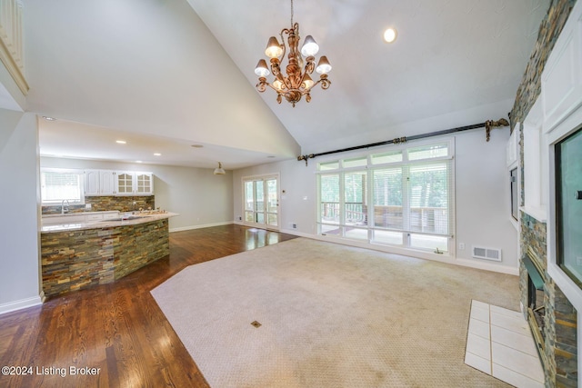 living room with sink, high vaulted ceiling, dark carpet, and an inviting chandelier