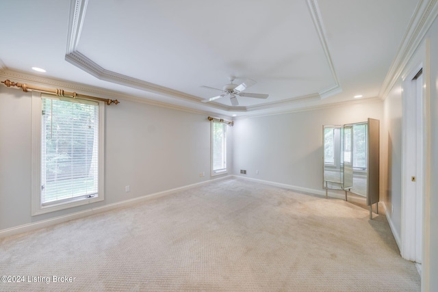 spare room with ceiling fan, crown molding, light colored carpet, and a tray ceiling