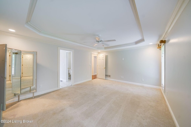 unfurnished bedroom featuring ceiling fan, crown molding, light colored carpet, and a tray ceiling