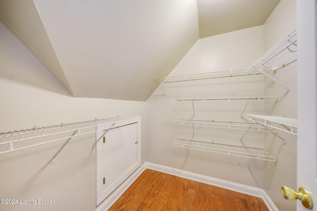 walk in closet with hardwood / wood-style floors and vaulted ceiling