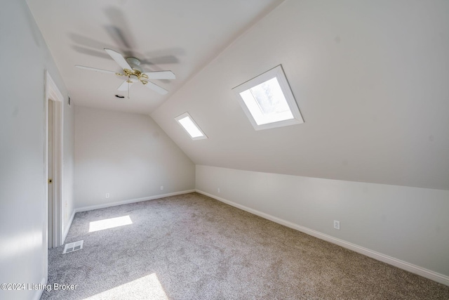 additional living space with ceiling fan, carpet floors, and lofted ceiling with skylight