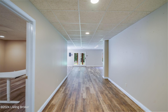 hallway featuring hardwood / wood-style floors, a paneled ceiling, and french doors