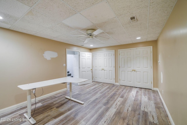 interior space with ceiling fan, hardwood / wood-style flooring, and a drop ceiling